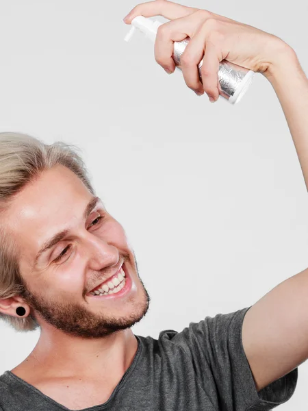 Hombre aplicando spray cosmético a su cabello — Foto de Stock