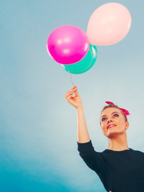 Tatlı gülümseyen kız renkli balonlar tutar.