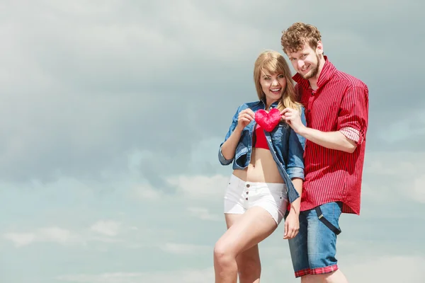 Pareja en amor sostiene rojo corazón al aire libre — Foto de Stock