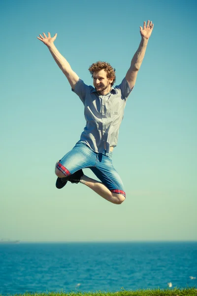 Carefree man jumping by sea ocean water. — Stock Photo, Image