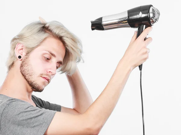 Anak muda mengeringkan rambut dengan pengering rambut — Stok Foto