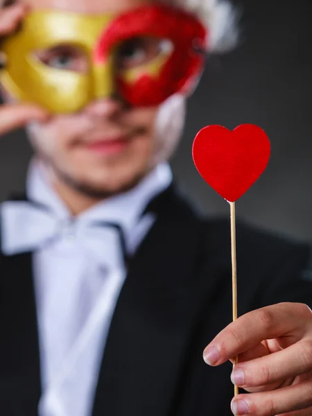 Людина в карнавальній масці з символом любові серця — стокове фото