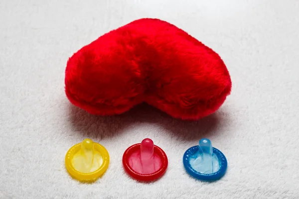 Kolorowy prezerwatywy i czerwone serce — Zdjęcie stockowe