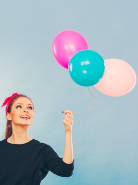 Tatlı gülümseyen kız renkli balonlar tutar.