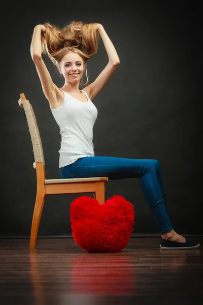 Happy woman with heart shaped pillow on floor — Stok fotoğraf