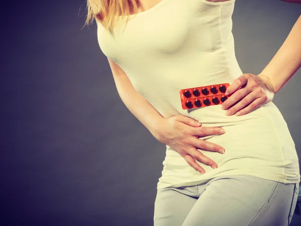 Kobieta cierpi z powodu brzucha ból trzyma pigułki — Zdjęcie stockowe