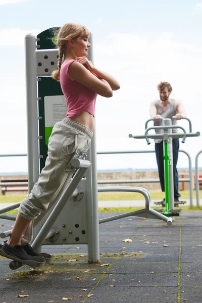 Mujer activa haciendo ejercicio en backtrainer al aire libre . — Foto de Stock