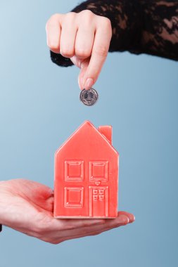 İnsanlar elleriyle küçük ev ve gümüş sikke.