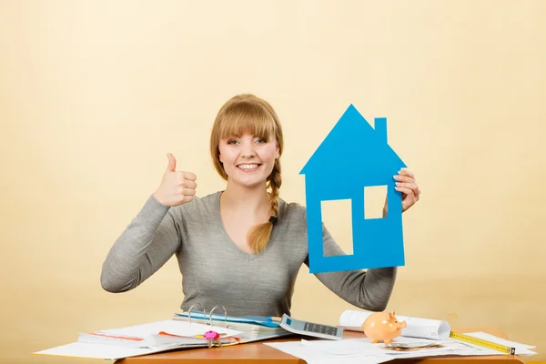 Happy woman holding house model.