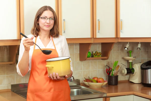 Mulher com concha e panela na cozinha — Fotografia de Stock