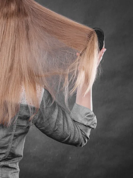 Blond kvinna kammar sitt hår. — Stockfoto