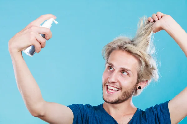 Hombre aplicando spray cosmético a su cabello — Foto de Stock