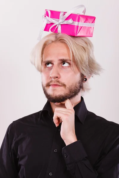 Tänkande kille med rosa presentförpackning på huvudet — Stockfoto