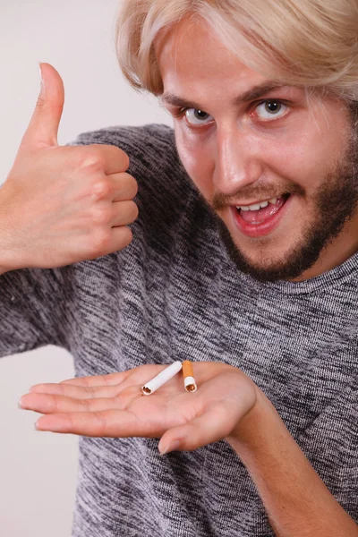 Man with broken cigarette on palm making thumb up — Stock Photo, Image