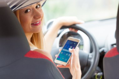 Arabasını kullanırken telefonu kullanan bir kadın.