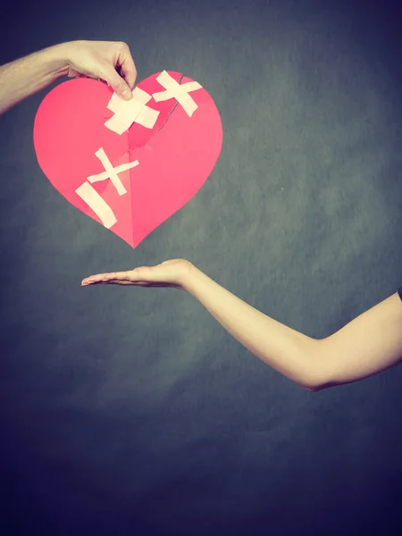 Woman and man hands holds broken heart. — Stock Photo, Image