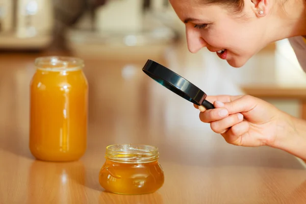 Mujer inspeccionando miel con lupa . —  Fotos de Stock
