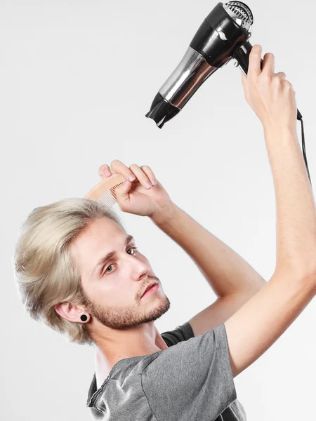 Joven hombre secando el cabello con secador de pelo — Foto de Stock