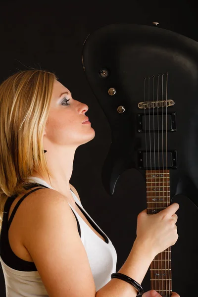Blondýny žena drží elektrickou kytaru, černé pozadí — Stock fotografie