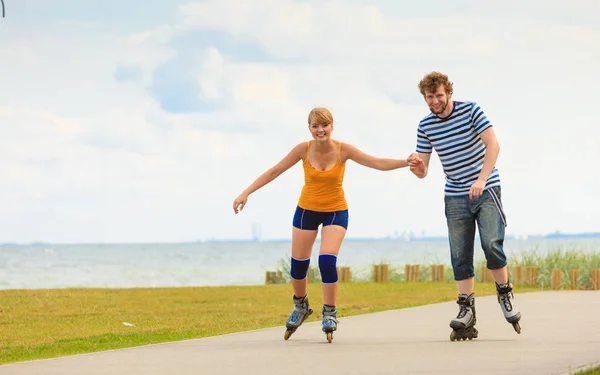 Pareja joven en patines de ruedas montando al aire libre —  Fotos de Stock