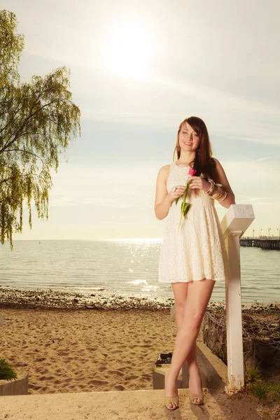 Mujer de pie en la playa sosteniendo tulipán rosa —  Fotos de Stock