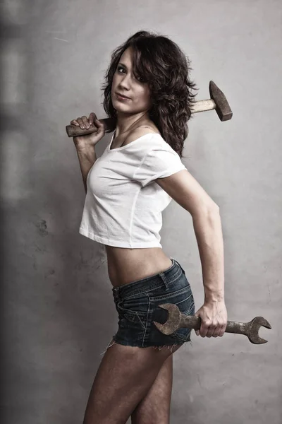 Sexy girl holding hammer and wrench spanner — Stock Photo, Image