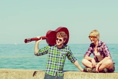 Genç adam onun kız arkadaşı deniz kenarında gitar çalmak