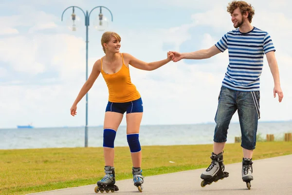 Jovem casal em patins andando ao ar livre — Fotografia de Stock