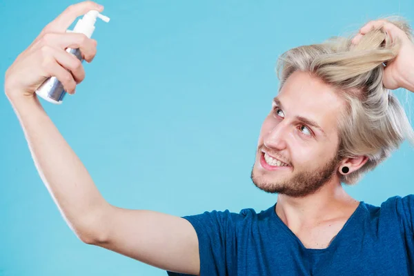 Hombre aplicando spray cosmético a su cabello — Foto de Stock
