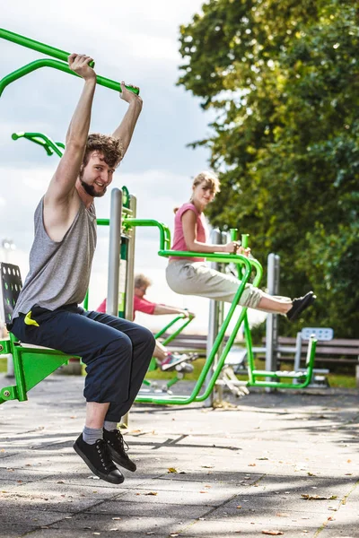 Active man and woman exercising at outdoor gym.