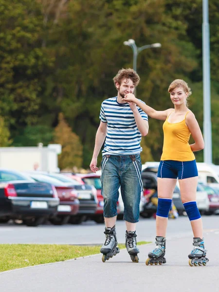 Pareja joven en patines de ruedas montando al aire libre — Foto de Stock