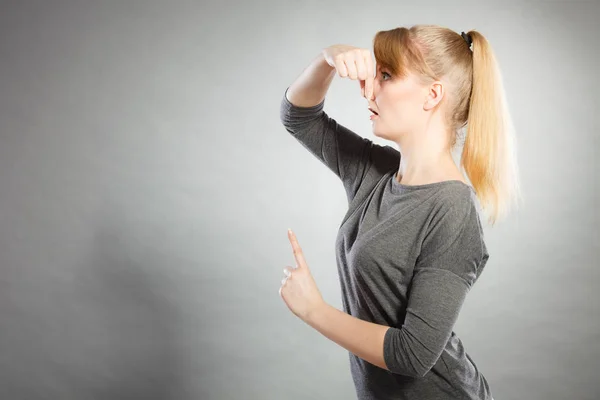 Blonde girl holding nose. — Stock Photo, Image