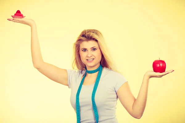 Woman choosing between cupcake and apple — Stock Photo, Image