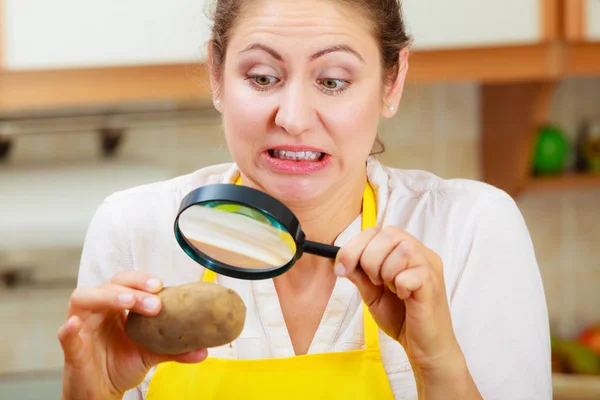 Женщина осматривает картофель с лупой . — стоковое фото