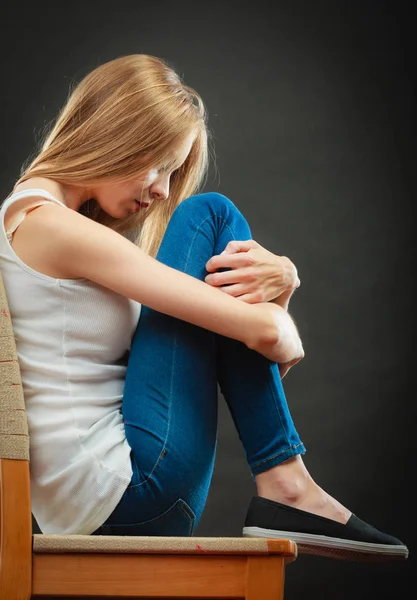 Jovem mulher triste sentada na cadeira — Fotografia de Stock