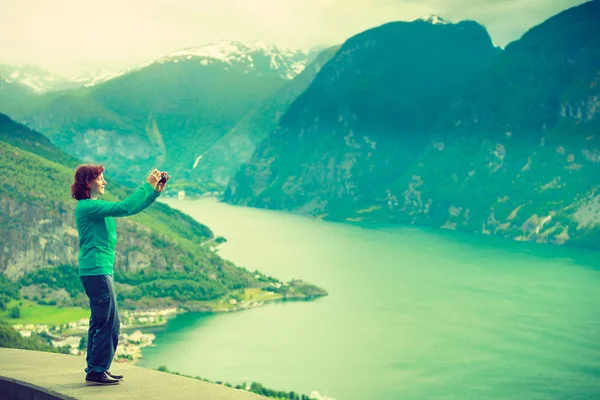 Kvinnlig turist tar foto på norsk fjord — Stockfoto