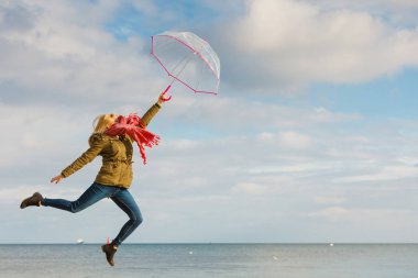 Kadın ile şeffaf şemsiye plajda atlama