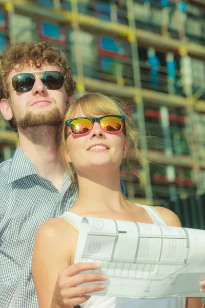 Pareja en frente de casa nueva con proyecto de anteproyecto — Foto de Stock