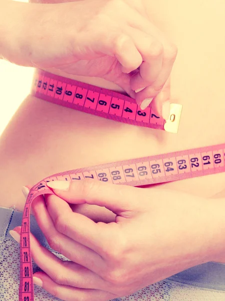 Femme en lingerie mesurant sa taille avec du ruban à mesurer . — Photo