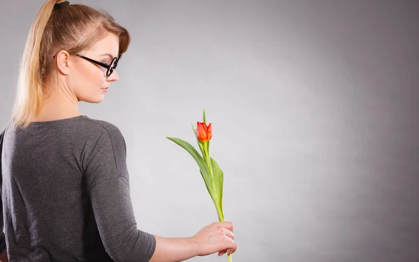 Blonde woman with single tulip. — Stock Photo, Image