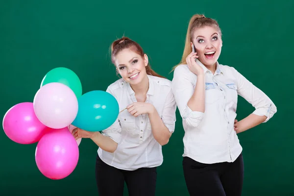 Две девушки с мобильным телефоном и воздушными шарами — стоковое фото