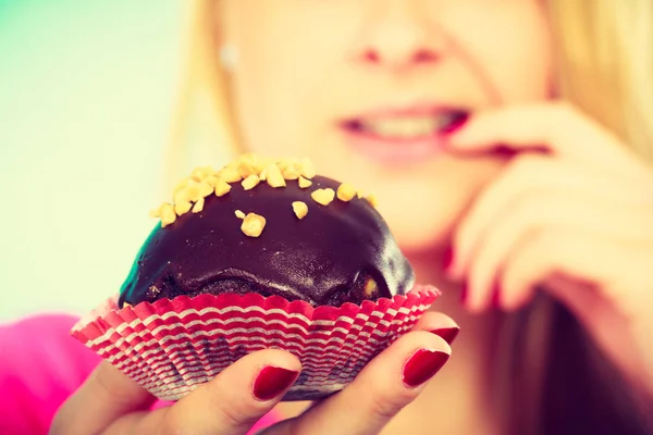 Carino donna bionda pensando di mangiare cupcake — Foto Stock
