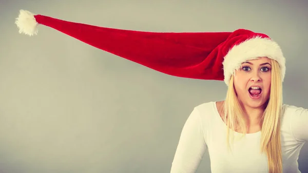 Surprised girl wearing blowing santa claus hat — Stock Photo, Image