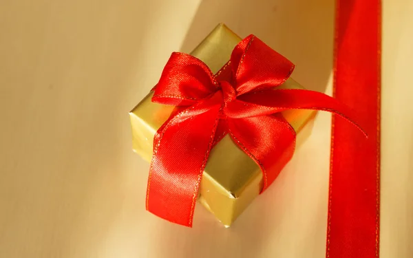 Küçük altın kutu hediye ile kırmızı yay bağlı — Stok fotoğraf