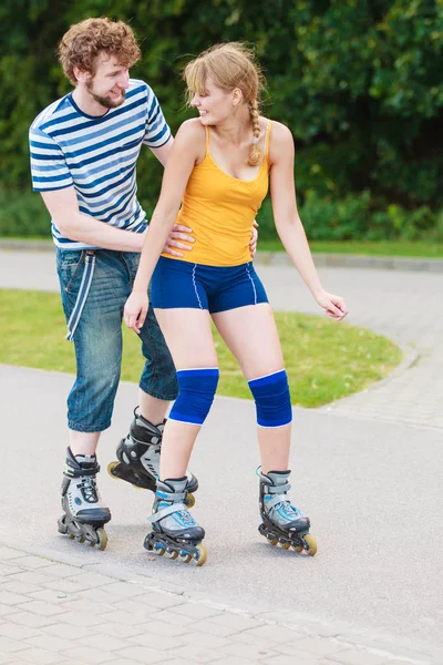 Pareja joven en patines de ruedas montando al aire libre — Foto de Stock