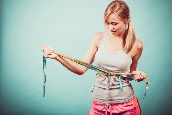 Fitness girl measuring her body with tapes — Stock Photo, Image