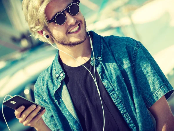 Blonde man in sunglasses listening to music — Stock Photo, Image