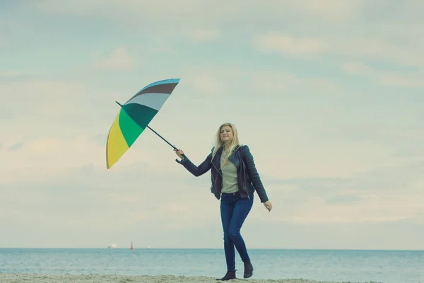 Kobieta trzyma kolorowy parasol na plaży — Zdjęcie stockowe