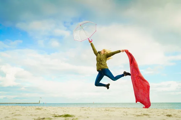 Femme heureuse sautant avec écharpe sur la plage — Photo