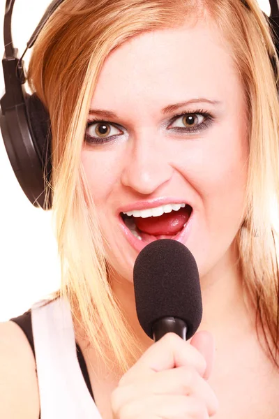 Woman singing to microphone wearing headphones — Stock Photo, Image